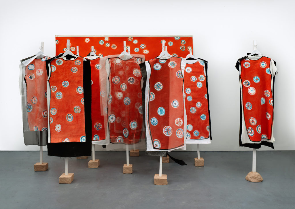 Lisa Milroy, Party of One, 2013, installation painting and painting performed. 9 dress object-paintings, 1 wearable dress painting, 10 wooden stands, clay bases. Oil on unstretched canvas, 182 x 234 cm x 2 m (71 ¾ x 92 ¼ x 78 ¾ in). Photography by Benjamin Westoby.
